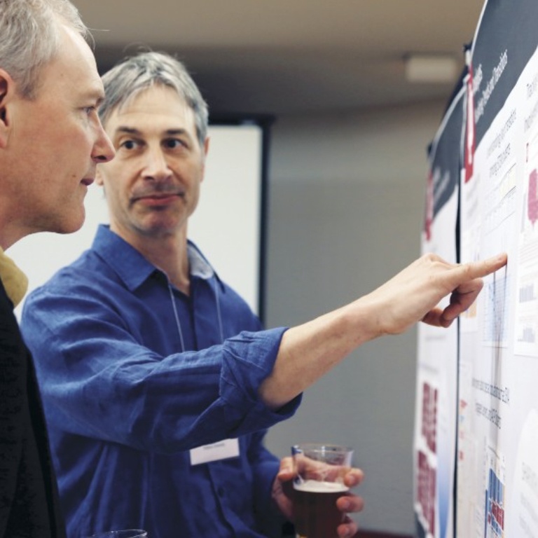 Mike Sauer points to a data visualization poster at a meeting of the Learning Analytics Fellows